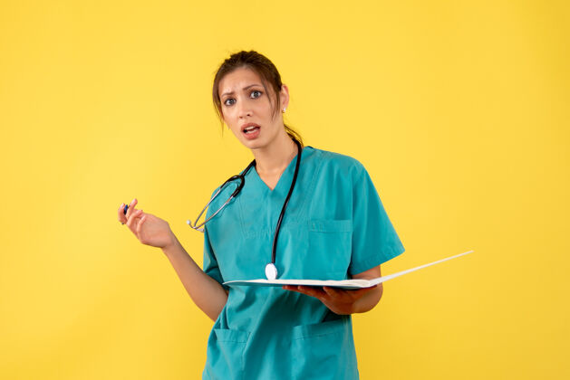 健康前视图穿着医用衬衫的女医生拿着黄色背景上的笔记衬衫情绪女医生
