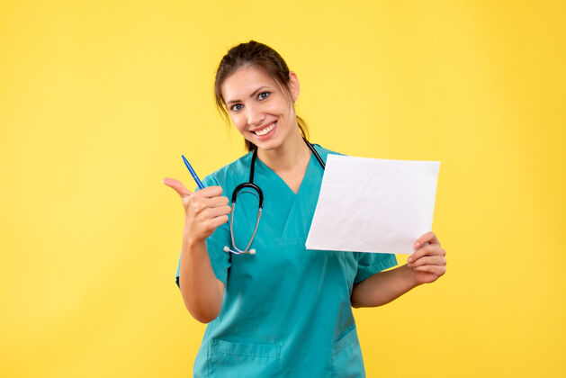 医生正面图黄色背景下穿着医疗衬衫的女医生拿着论文分析持有黄色病毒