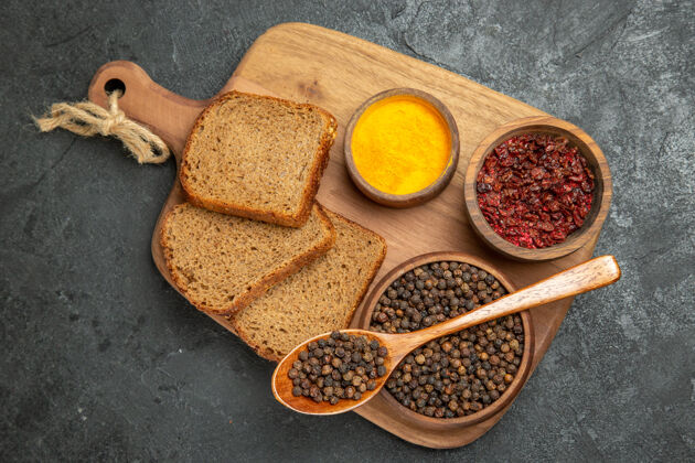 小吃顶视图不同的调味品与面包面包面包放在灰色的桌子上辛辣辣的面包勺子原料胡椒粉
