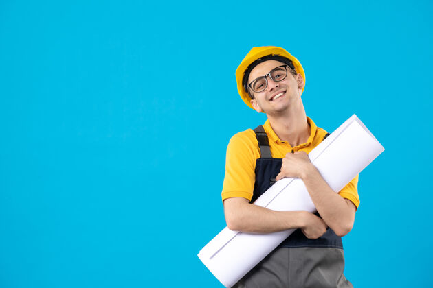 职业身着黄色制服 蓝色平面图的微笑男建筑工人正面图工程师计划工作