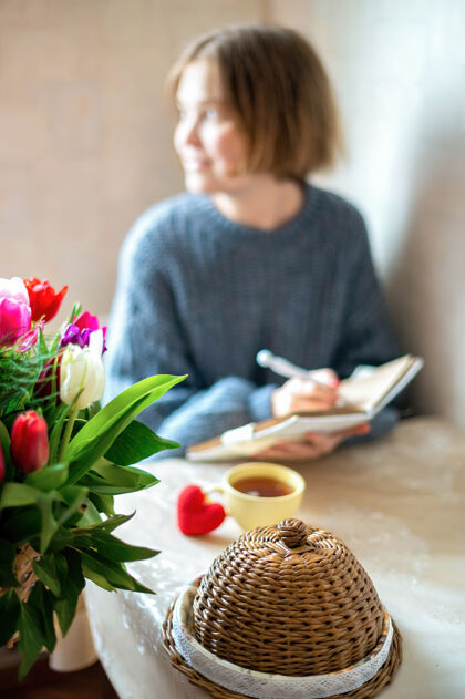 白天织红心和一杯茶放在桌上 一个女孩拿着笔记本厨房室内生活创意
