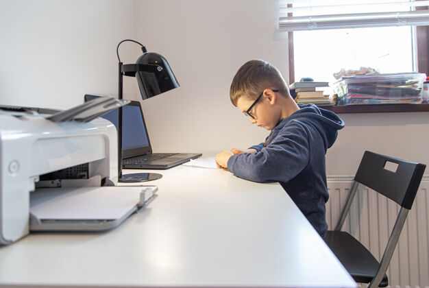 笔记本电脑一个小学生在家里对着桌上的笔记本电脑远程学习教育男孩室内
