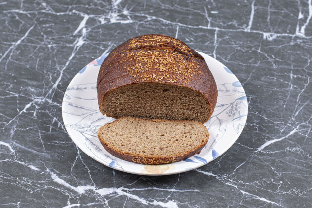 食材美味的黑面包和芝麻在盘子上 在大理石表面芝麻面粉美味