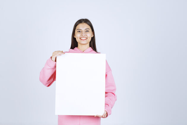 年轻人穿着粉色睡衣的女孩 手里拿着一块空白的方形展示板表演成人Thinkboard