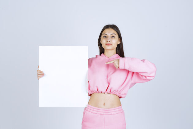 女人穿着粉色睡衣的女孩拿着一块空白的正方形展示板 指着它雇员装装装人类