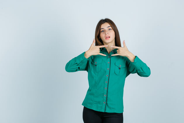 个人身穿绿衬衫的年轻女性展现出摇滚的姿态 看起来很自信 正面照商业人物表演