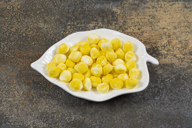 糖果美味的黄色糖果放在叶子形状的盘子里甜点零食水果