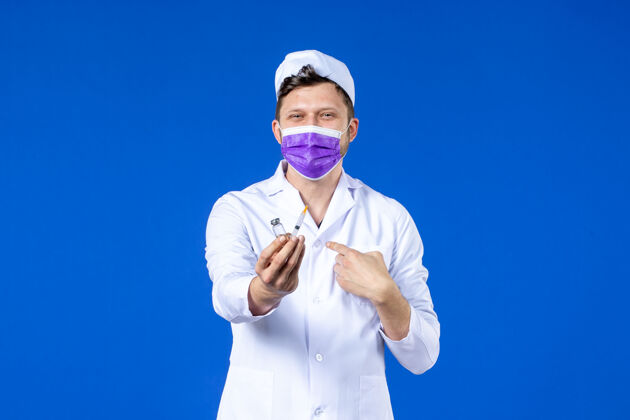 外套男医生的前视图 穿着医疗服 戴着蓝色的注射和疫苗面罩疫苗病毒医院