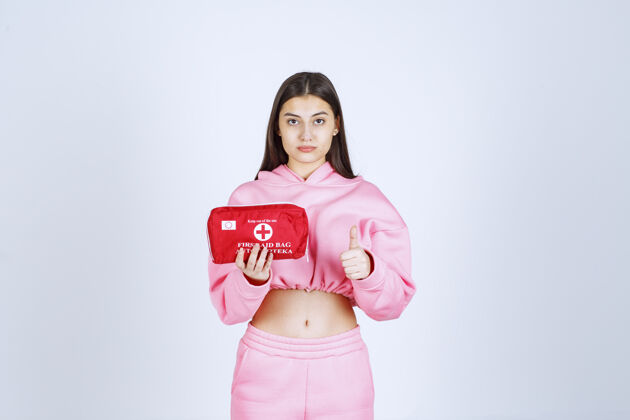 模特穿着粉色睡衣的女孩拿着一个红色的急救箱在宣传人营销方便