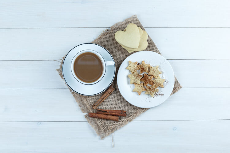 早餐一套饼干 肉桂棒和咖啡在一个木杯和布袋背景顶视图泡沫木头味道