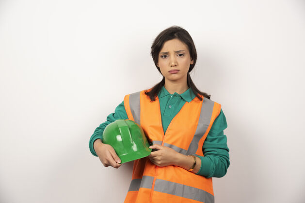 女士沮丧的女工程师拿着白色背景的头盔工作专业企业