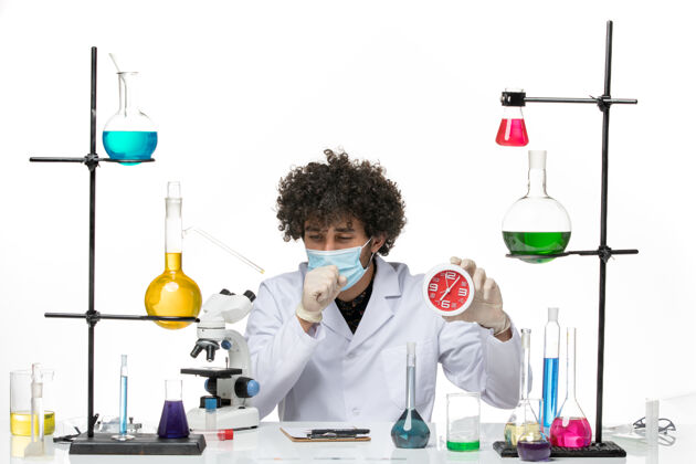 男性化学家正面图：男药剂师穿着医疗服 戴着面罩 拿着红色的时钟 在空白处咳嗽男性化学医学