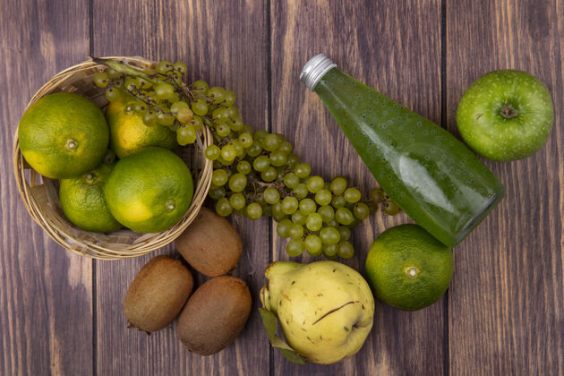 猕猴桃顶视图果汁瓶与梨 猕猴桃 橘子 苹果和葡萄在一个篮子在一个木墙上瓶子篮子景观