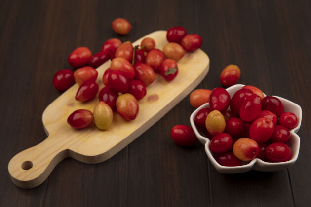 木材木制厨房板上的小甜馅饼山茱萸樱桃顶视图 木制表面的碗上有山茱萸樱桃碗健康小