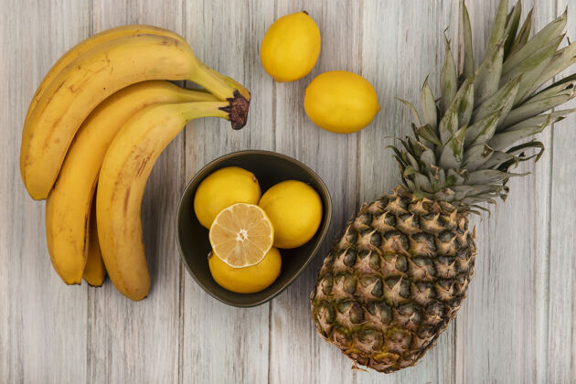 营养顶视图新鲜多汁的柠檬与菠萝香蕉和柠檬隔离在一个灰色的木制表面碗健康柠檬菠萝