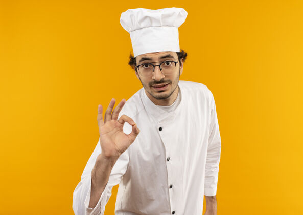 制服年轻的男厨师穿着厨师制服 戴着眼镜 摆出一副很好的姿势黄色烹饪眼镜