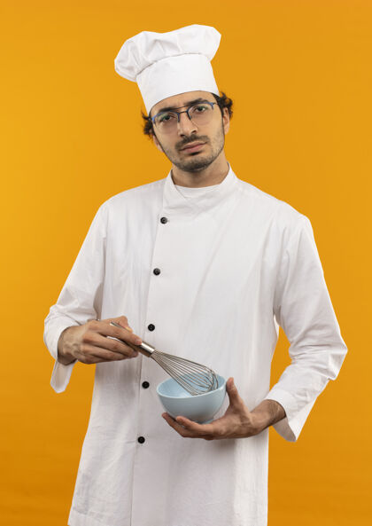 穿自信的年轻男厨师 穿着厨师制服 戴着玻璃杯 手里拿着威士忌和碗烹饪拂男人