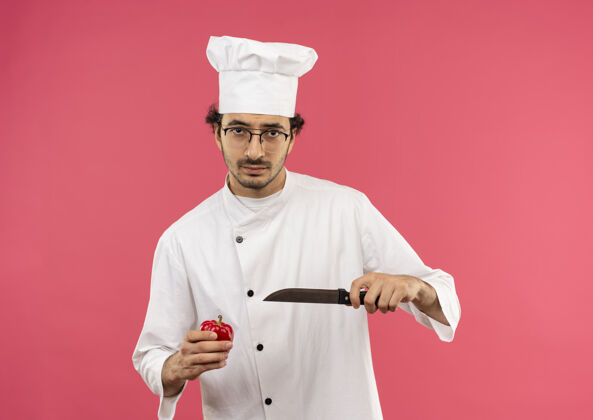 制服年轻的男厨师穿着厨师制服 戴着眼镜 手里拿着刀和胡椒粉年轻胡椒刀