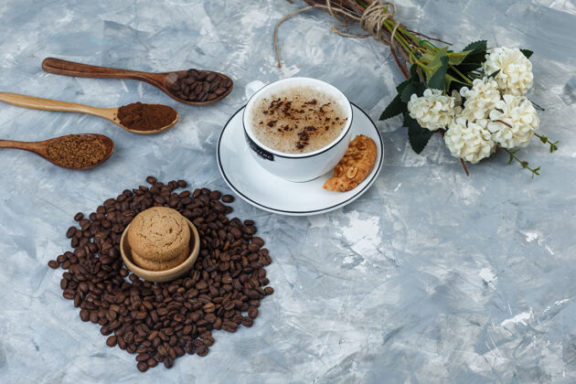 质地一套饼干 咖啡豆 磨碎的咖啡 鲜花和咖啡杯在一个肮脏的灰色背景高角度视图浓缩咖啡拿铁豆类