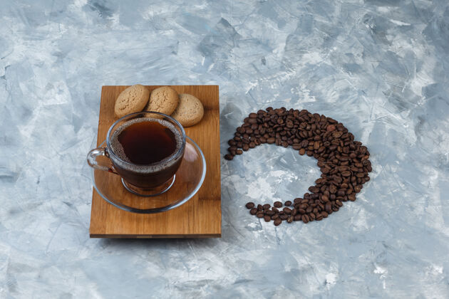 大笑高角度观看咖啡杯 饼干放在木制砧板上 咖啡豆放在浅蓝色大理石背景上水平拿铁食物大理石