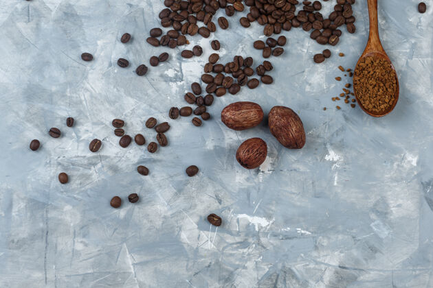 意式咖啡咖啡粉和咖啡豆放在木勺里 饼干放在浅蓝色大理石背景上顶视图木头大理石豆子