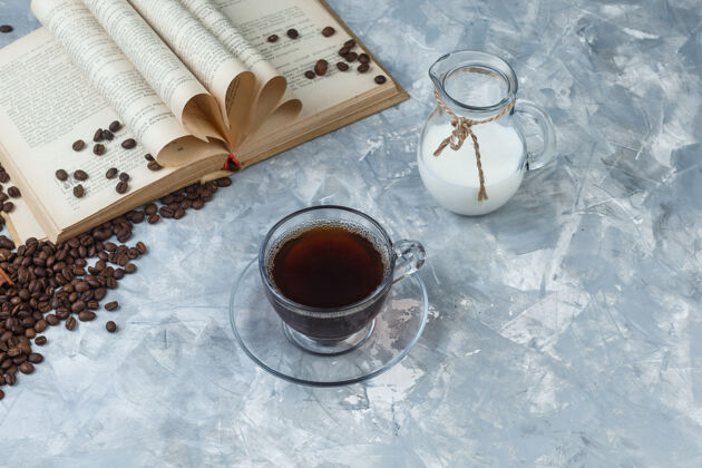 堆高角度看咖啡杯 咖啡豆 书 牛奶在灰色背景上水平高杯子能量