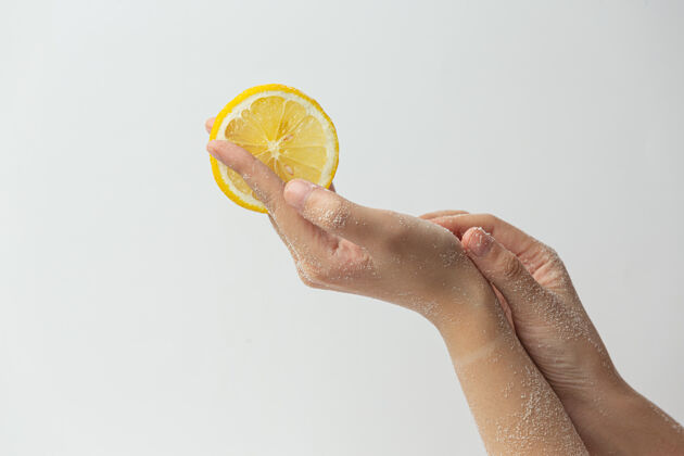 健康年轻女子用天然柠檬磨砂膏擦手上的白色表面皮肤人年轻