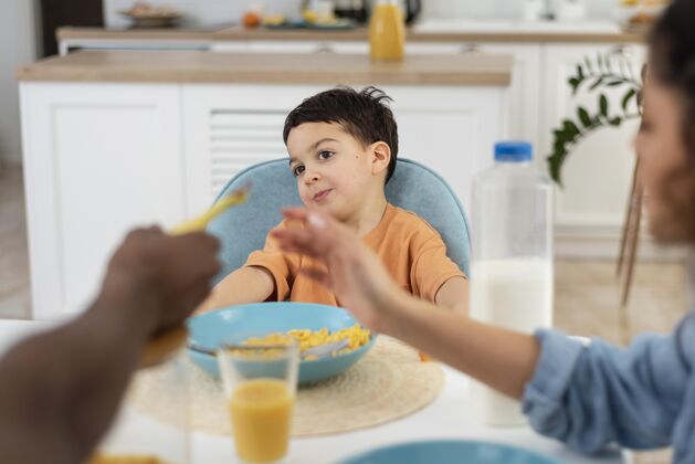 女人可爱的小男孩和父母一起吃早餐的照片熟悉父母家庭