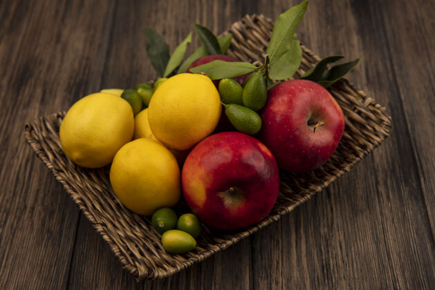 健康健康水果的顶视图 如苹果 柠檬和金盏花 放在木质表面的柳条托盘上柳条柠檬美味