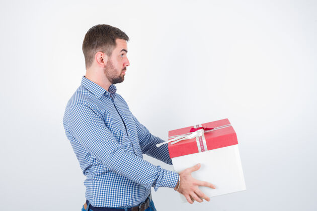 焦点年轻男子拿着礼盒在衬衫和困惑的样子前视图男人礼物头