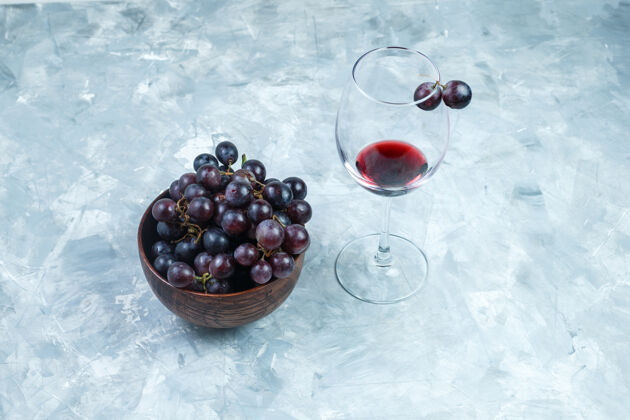 水果一杯葡萄酒和黑葡萄放在一个粘土碗里 背景是灰色的 高角度的视角葡萄酒庄串