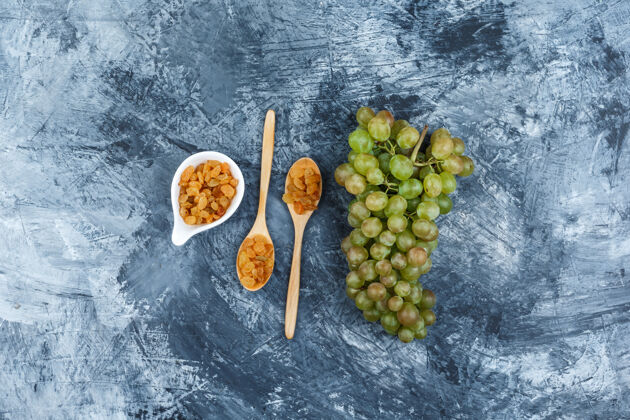 食物一套葡萄干和绿色葡萄在一个肮脏的石膏背景顶视图叶子甜点美味