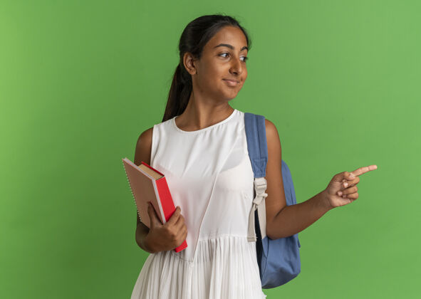 持有看着身边高兴的小女生背着书包拿着笔记本指着身边年轻绿色穿