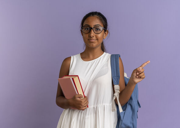 戴年轻的女学生背着书包戴着眼镜拿着书指着身边学生女生壁板
