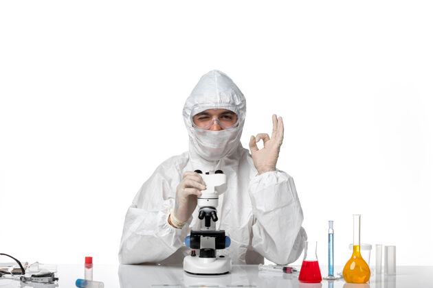显微镜正面图：男医生穿着防护服 戴着面罩 用显微镜在空白处微笑使用专业外套