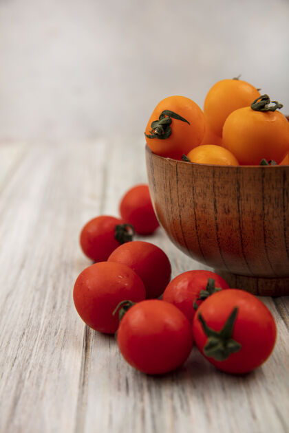 有机侧视图橙色西红柿在一个木碗与红色西红柿隔离在一个灰色的木制表面番茄美味蔬菜