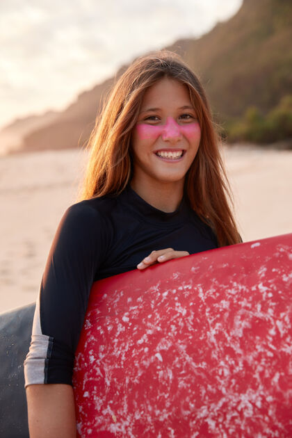冲浪垂直拍摄的美丽微笑的女人与吸引力的外观海岸射击海洋