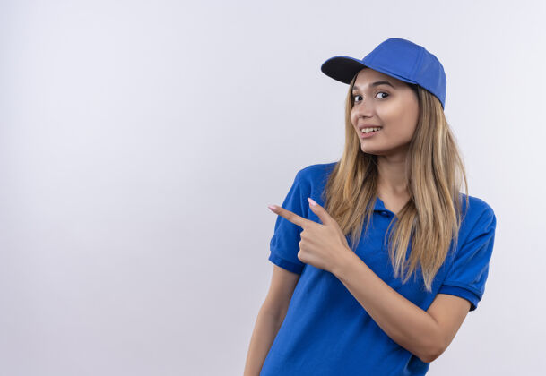 年轻带着微笑的年轻送货员身穿蓝色制服 戴着帽子 站在白色墙壁上 留着复印空间穿女孩帽子