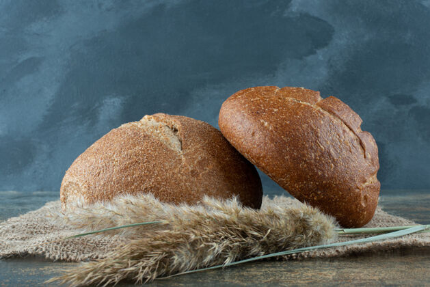 麻布两个新鲜的棕色面包和麻布上的小麦美味小麦面包