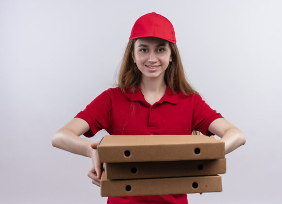 分娩微笑着的年轻送货女孩穿着红色制服 在孤立的白色墙上伸展包裹年轻制服盒子
