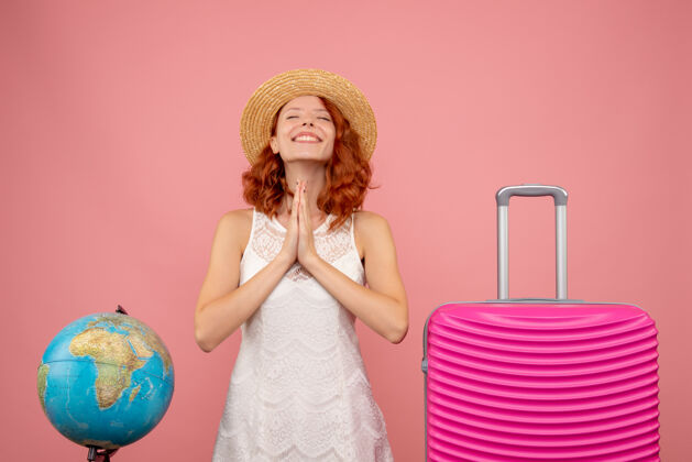 包年轻的女游客与粉红色的袋子微笑和粉红色的墙上祈祷的正面视图人时尚旅行