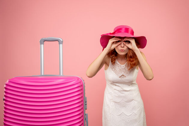 情感年轻的女性游客与粉红色的帽子和粉红色的墙壁上的包的正面视图微笑快乐人