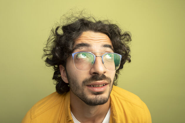 男人在橄榄绿的墙上 一个年轻英俊的白种人戴着一副眼镜 抬头仰望 给人留下了深刻印象特写眼镜帅气
