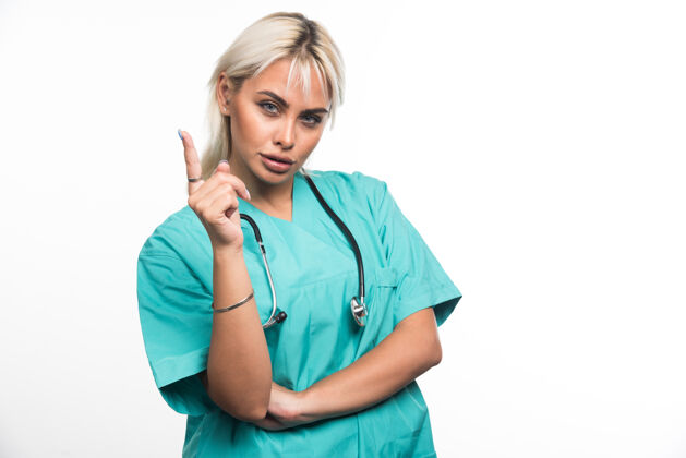 女性女医生用听诊器指着白色表面工作站立女士