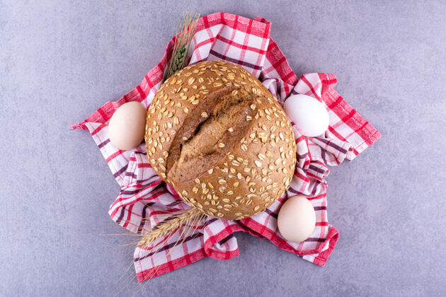 口味麦秆鸡蛋和面包放在大理石表面的毛巾上小麦烘焙食品谷物