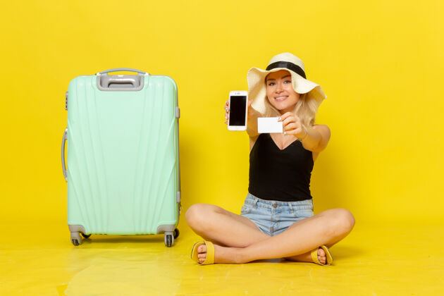 成人正面图年轻女子手持白卡和手机黄色旅行微笑