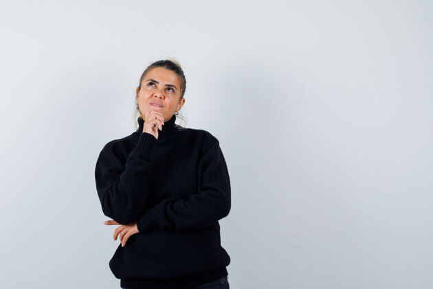 年轻年轻的女性穿着黑色高领毛衣站在思考的姿势 看起来沉思 正面视图女士正面工作