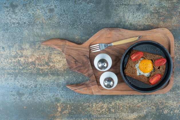 叉子一个深色的平底锅 上面放着煎鸡蛋和棕色面包片可口切片西红柿