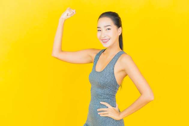 中国在黄色的墙上 描绘一位穿着运动服准备锻炼的美丽亚洲年轻女子身体模特活跃