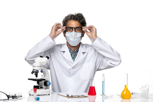 实验室前视图穿着白色医疗服的中年科学家围坐在桌子旁 拿着解决方案男性实验套装
